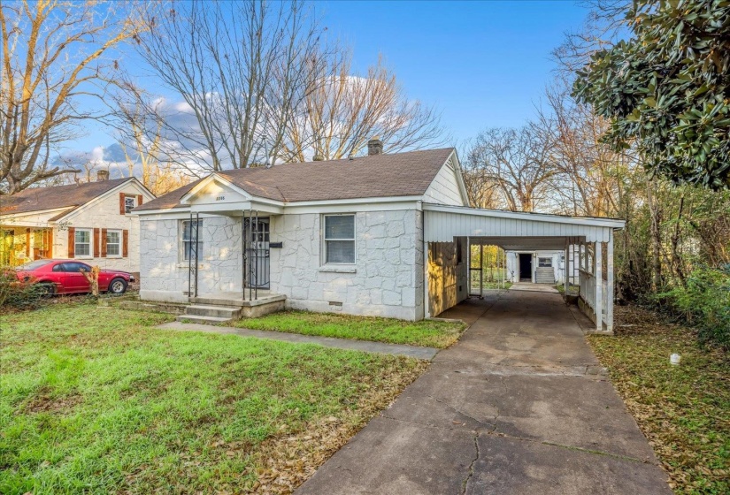 View of front of house with a chimney, a front lawn, a shingled roof, concrete driveway, and a carport
