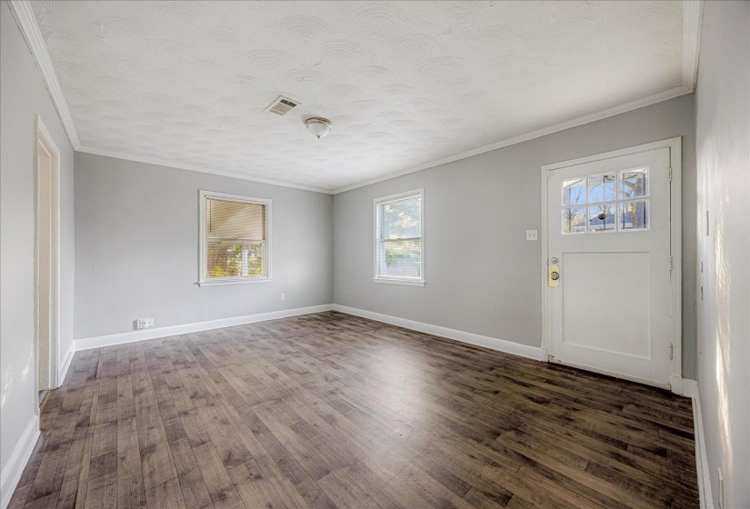 Entrance foyer with ornamental molding, dark wood-type flooring, and a textured ceiling