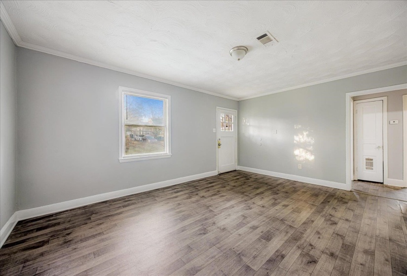 Spare room with wood finished floors, ornamental molding, and a textured ceiling