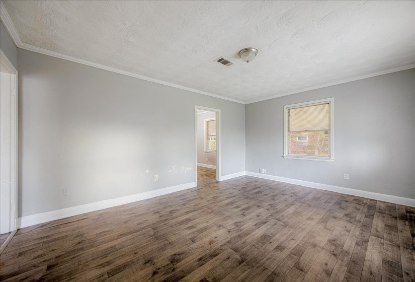 Unfurnished room featuring ornamental molding, wood finished floors, and a textured ceiling