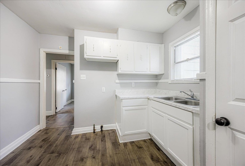 Kitchen with light countertops, white cabinetry, and dark wood-style floors
