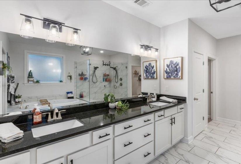 Full bath featuring double vanity, a marble finish shower, light marble finish flooring, and a bathtub