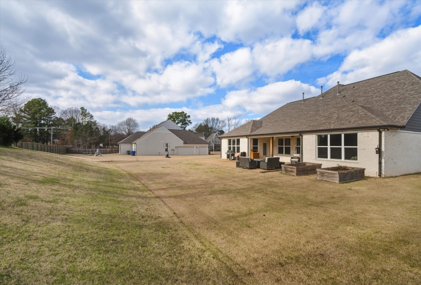 Rear view of property featuring a patio, brick siding, a shingled roof, a garden, and an outdoor living space