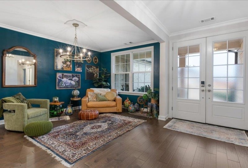 Foyer with french doors, crown molding, dark wood-style floors, and a chandelier