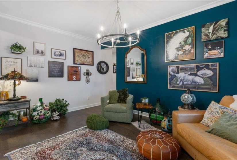 Living area featuring hardwood / wood-style floors, crown molding, and a chandelier