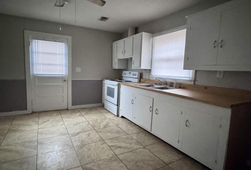 Kitchen with white cabinetry, electric stove, light countertops, and plenty of natural light