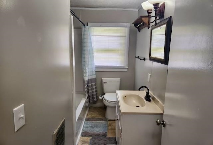 Full bathroom with toilet, vanity, shower / bath combo with shower curtain, tile patterned floors, and a healthy amount of sunlight