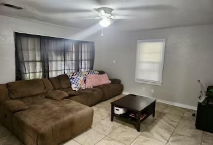 Living room featuring light tile patterned flooring and ceiling fan