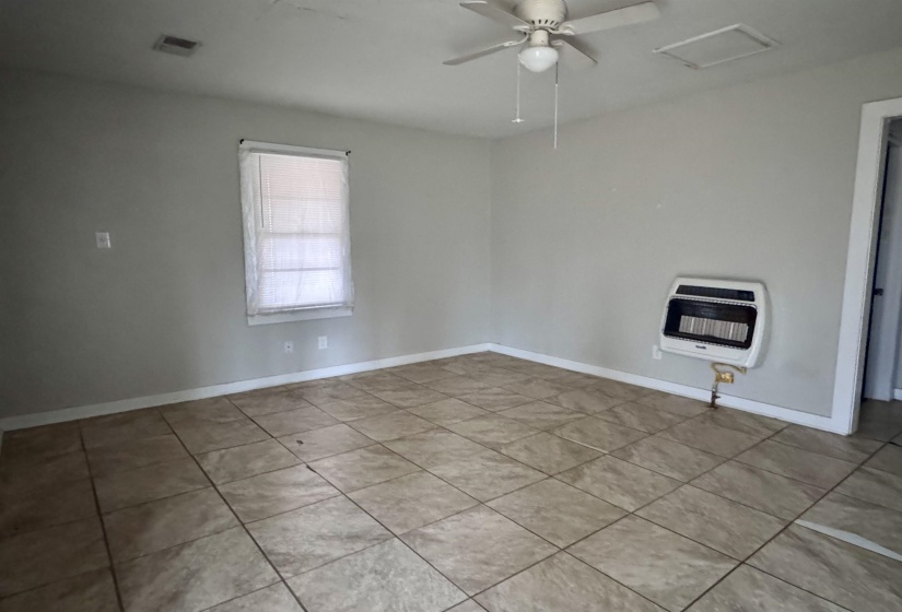 Unfurnished room featuring heating unit, attic access, ceiling fan, and light tile patterned floors