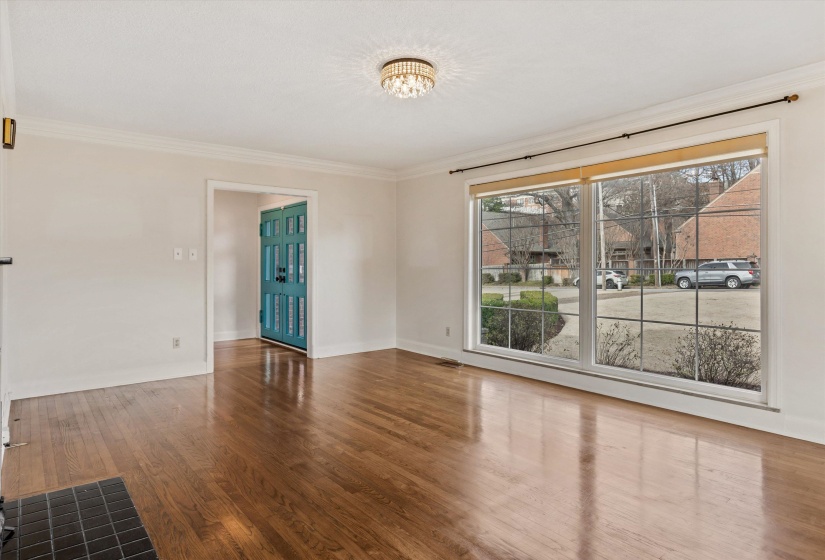 Room with crown molding, wood finished floors, and a chandelier