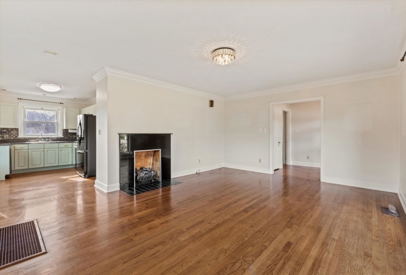 Unfurnished living room with a tile fireplace, crown molding, and light wood-style flooring