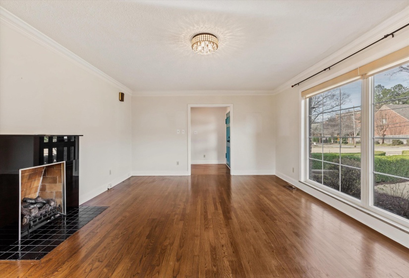 Unfurnished living room featuring ornamental molding, a tile fireplace, dark wood-style flooring, and a chandelier