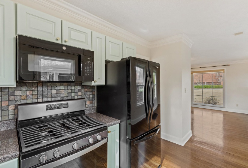 Kitchen featuring black appliances, crown molding, backsplash, light wood-type flooring, and white cabinets