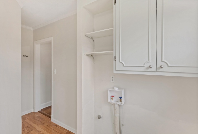 Laundry room featuring light wood finished floors, hookup for a washing machine, cabinet space, and crown molding