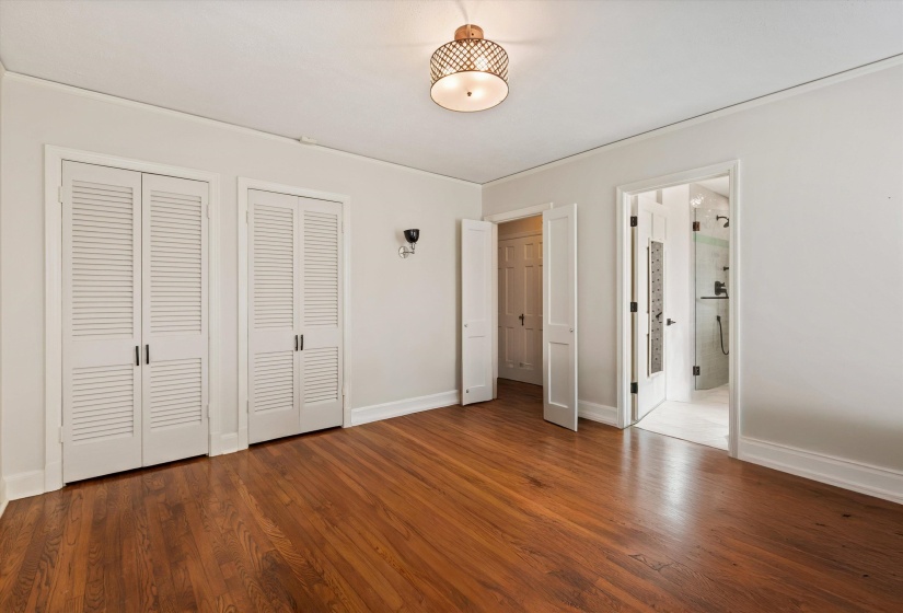 Bedroom featuring multiple closets, wood finished floors, and ensuite bath