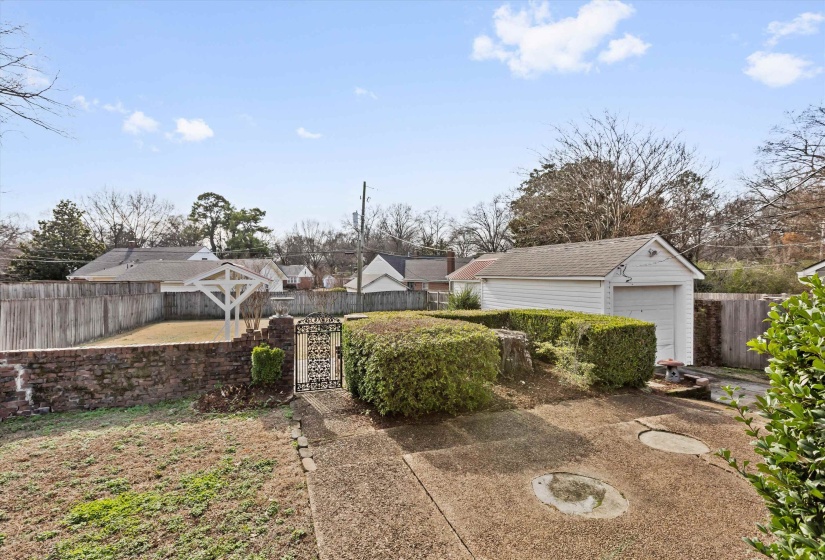 Fenced backyard featuring an outdoor structure, a garage, and a gate