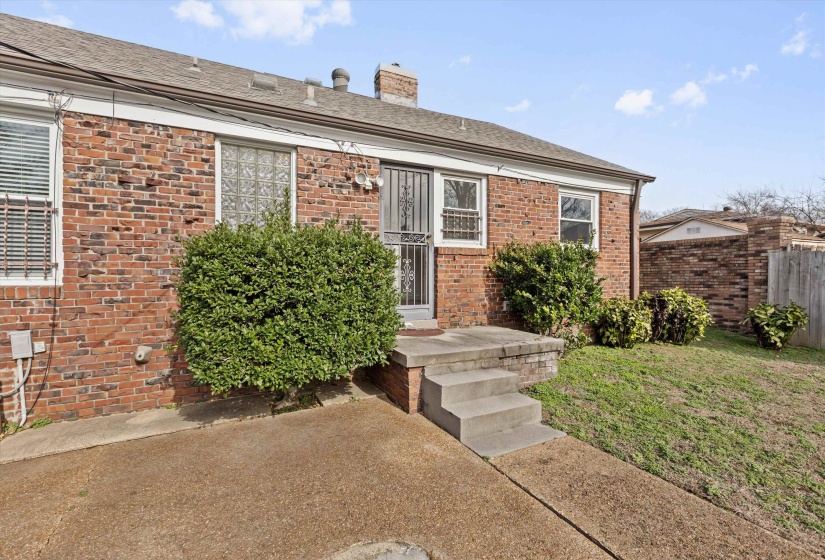 Doorway to property featuring brick siding and a chimney