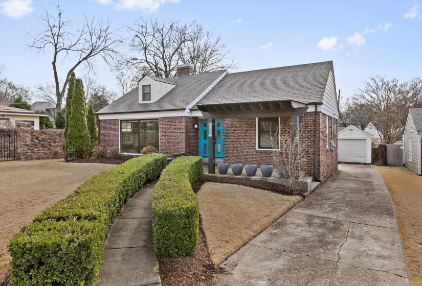 View of front facade with brick siding, a shingled roof, a chimney, concrete driveway, and a garage