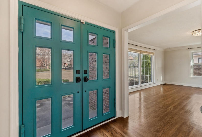 Foyer entrance with crown molding and dark wood-style flooring