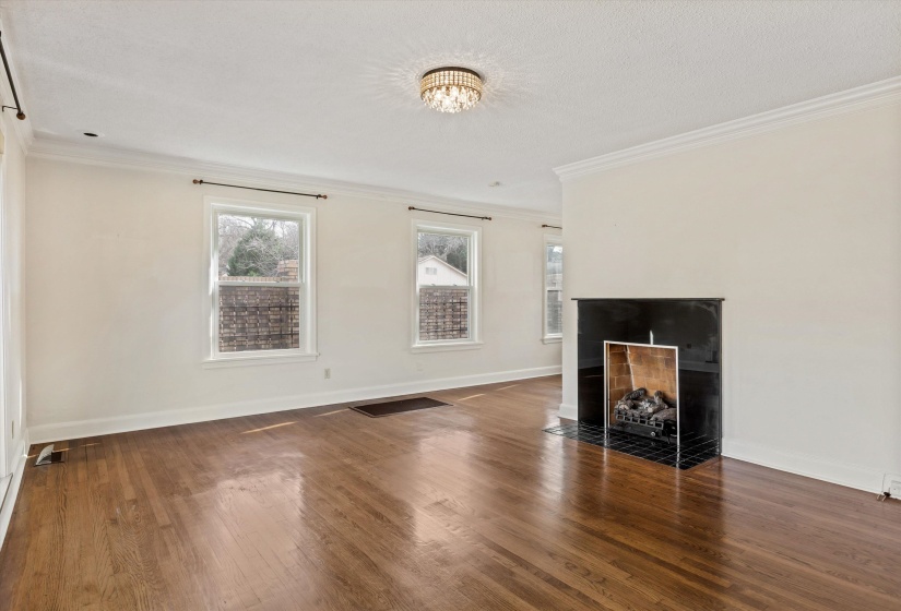 Unfurnished living room featuring crown molding, dark wood finished floors, and a fireplace with flush hearth