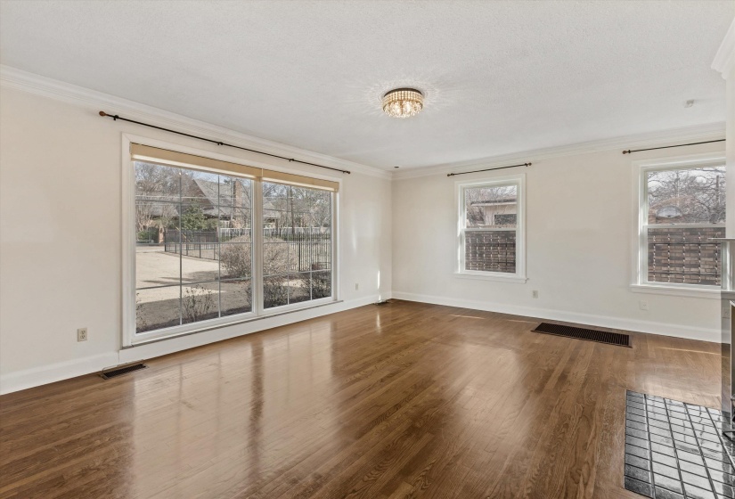 Room featuring crown molding, dark wood-style floors, and healthy amount of natural light