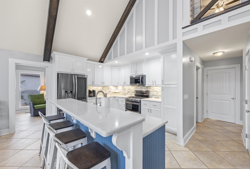 Kitchen featuring white cabinets, a breakfast bar area, appliances with stainless steel finishes, light tile patterned floors, and high vaulted ceiling