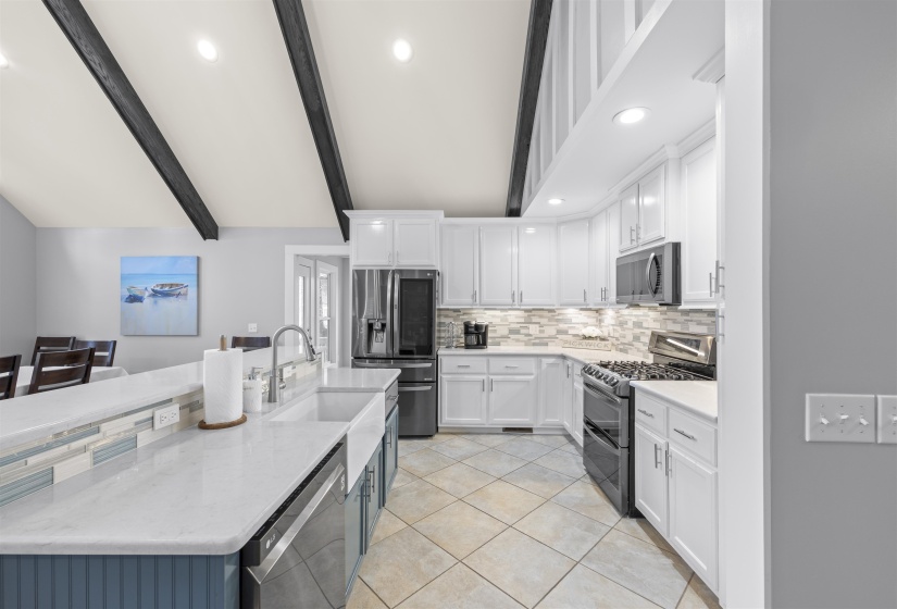 Kitchen with white cabinetry, light stone counters, stainless steel appliances, decorative backsplash, and recessed lighting