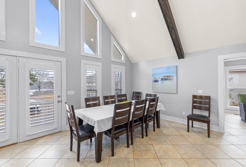 Dining space with healthy amount of natural light, high vaulted ceiling, light tile patterned floors, and beam ceiling