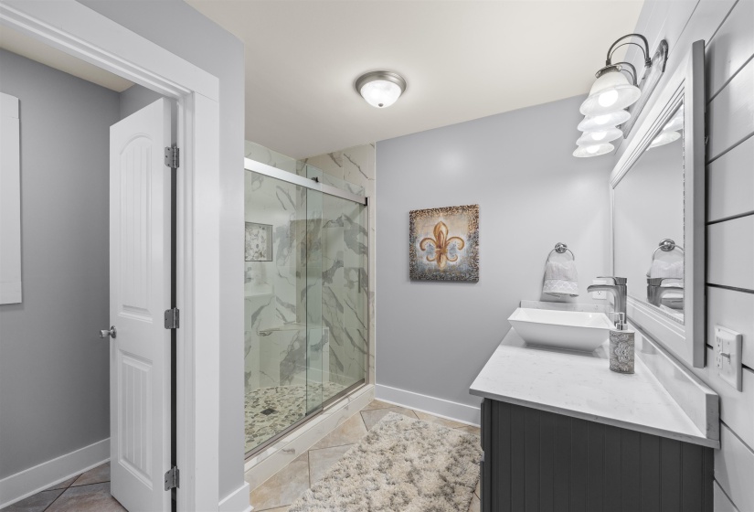 Bathroom featuring vanity and a marble finish shower
