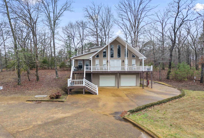 Chalet / cabin featuring stairs, a deck, driveway, and an attached garage
