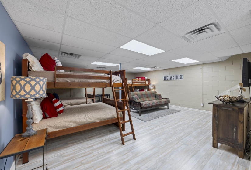 Bedroom featuring concrete block wall, light wood-type flooring, and a drop ceiling