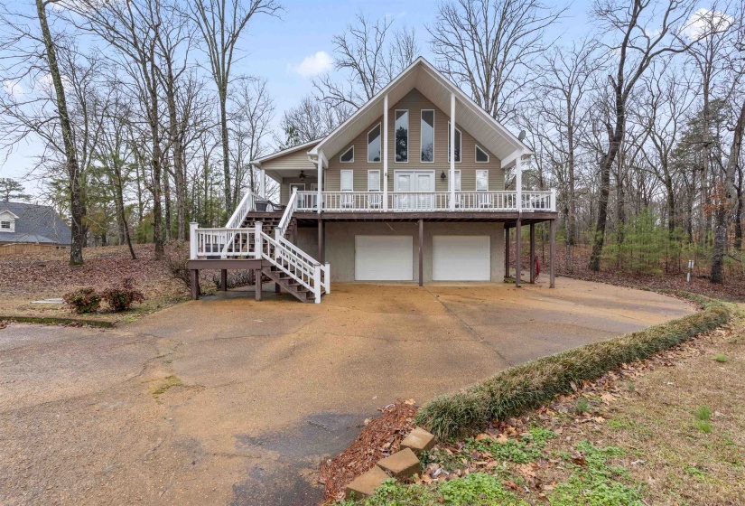 Rustic home with a deck, stairs, driveway, and an attached garage