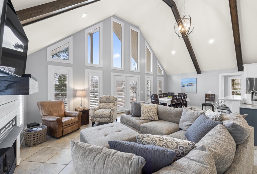 Living room featuring high vaulted ceiling, beamed ceiling, a fireplace, light tile patterned flooring, and recessed lighting