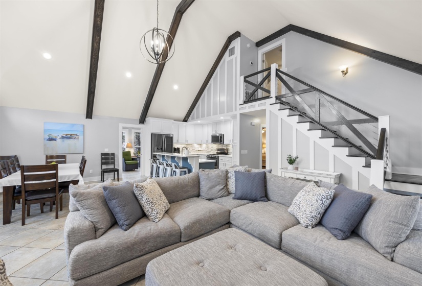 Living area with high vaulted ceiling, beam ceiling, stairs, a chandelier, and recessed lighting