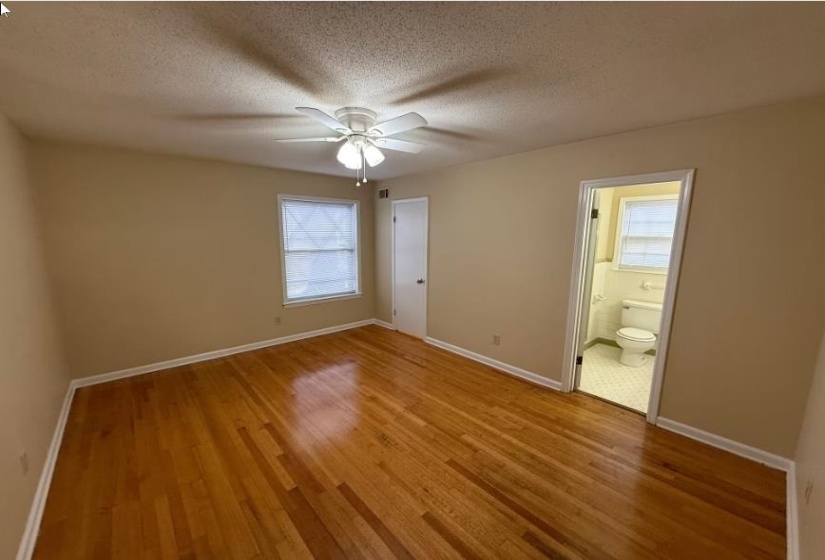 Unfurnished bedroom featuring light wood-style flooring, a textured ceiling, a ceiling fan, and connected bathroom