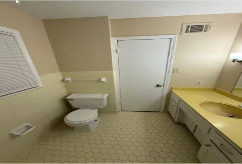 Half bathroom with vanity, light flooring, and wainscoting
