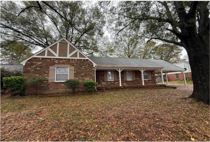 View of front of property with covered porch, brick siding, a carport, and roof with shingles