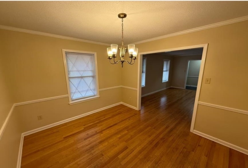 Unfurnished room featuring crown molding, wood finished floors, a chandelier, and a textured ceiling