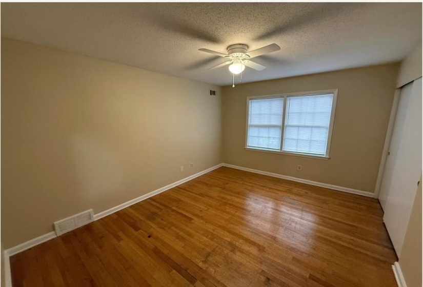 Unfurnished bedroom featuring light wood-style flooring, a textured ceiling, ceiling fan, and a closet