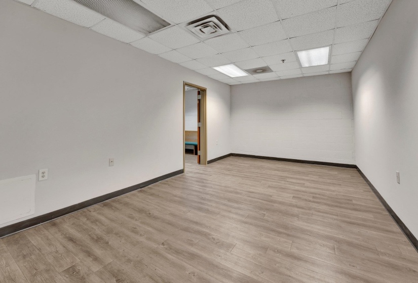 Empty room with light wood-type flooring and a drop ceiling
