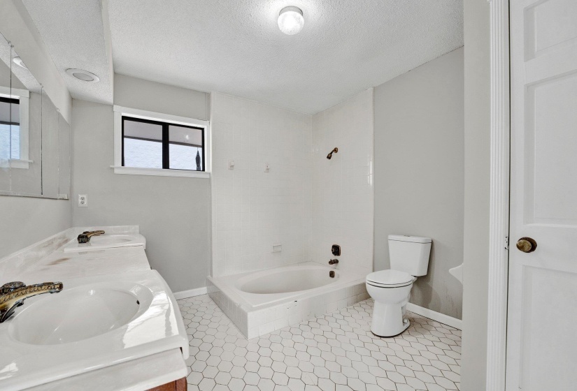 Bathroom with tile patterned flooring, a textured ceiling, toilet, and dual bowl vanity