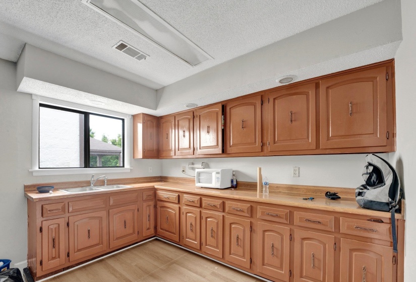 Kitchen with sink, a textured ceiling, and light hardwood / wood-style flooring