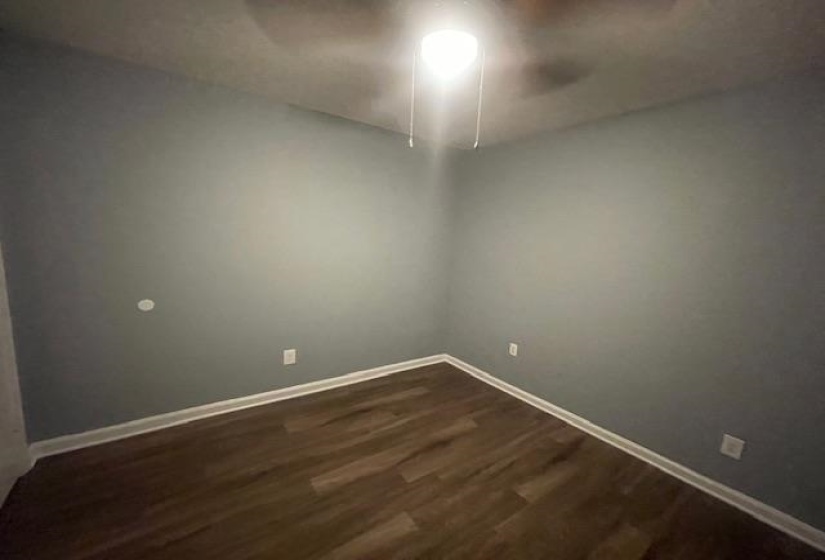 Empty room with dark wood-style floors and baseboards