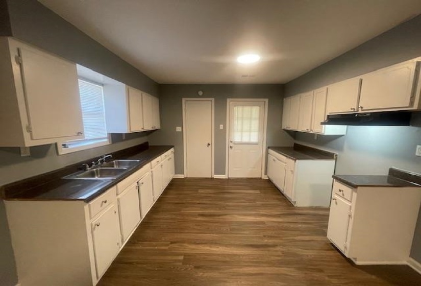 Kitchen featuring dark countertops, white cabinetry, dark wood-style flooring, and under cabinet range hood