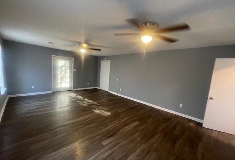 Empty room with dark wood-type flooring and baseboards