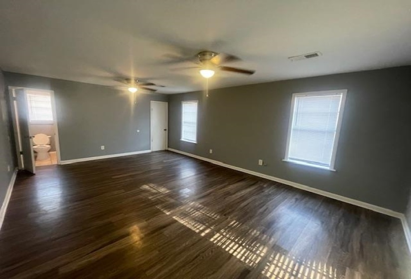 Empty room with dark wood-style floors and ceiling fan