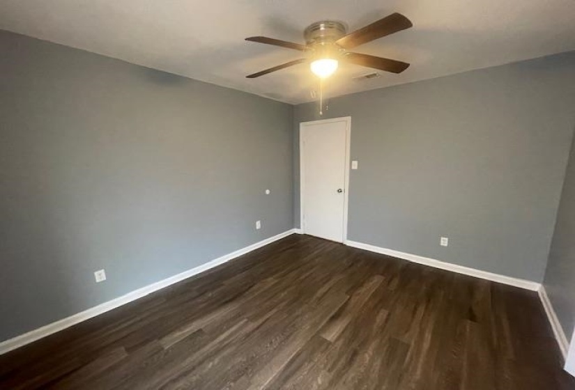 Empty room featuring dark wood finished floors and a ceiling fan