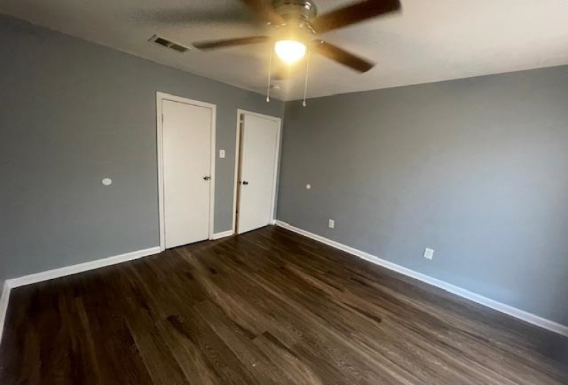 Unfurnished bedroom with ceiling fan, dark wood-style flooring, and a closet