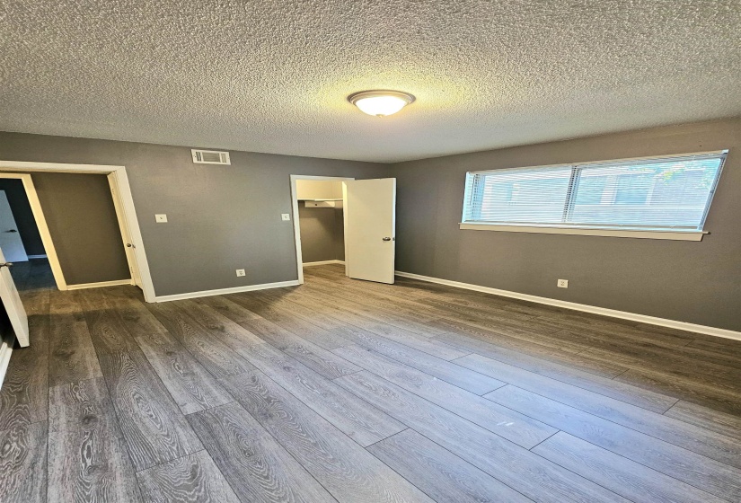 Unfurnished bedroom with a spacious closet, wood finished floors, and a textured ceiling