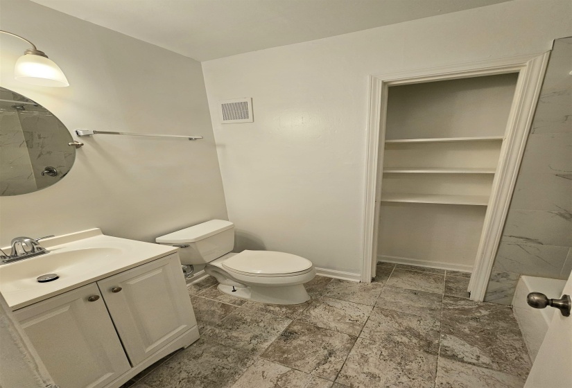 Full bath featuring a marble finish shower, vanity, and a walk in closet